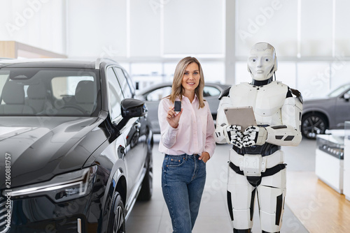 Foto A woman holds car keys while standing next to a humanoid robot in a modern car s