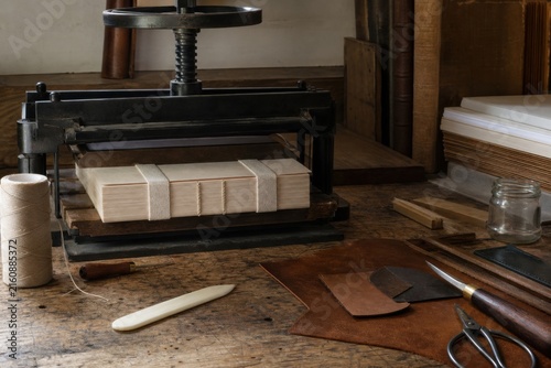 Traditional bookbinding bench with book press, linen thread and paper blocks, ideal for artisan publishing, restoration and handmade craft