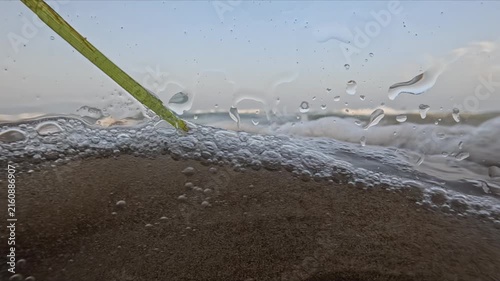 Ocean waves filmed from the waterline at sunset with underwater bubbles droplets and golden light captured in slow motion
