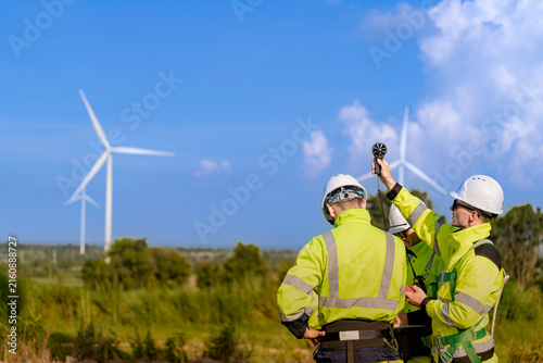 Foto Two wind energy workers take a wind speed reading together, one lifting the vane