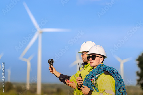 Fotografía A technician in sunglasses holds a wind meter at eye level while his colleague l