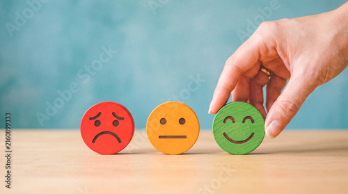 Hand selecting a happy face emoji from a row of emotion icons