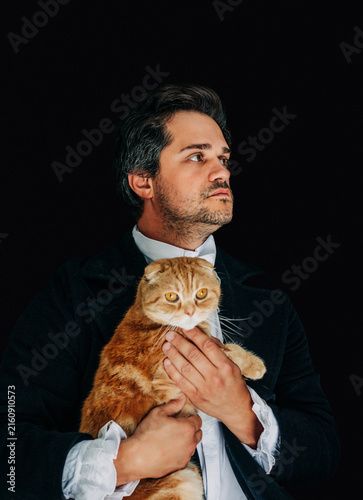 Photography 19th century European nobleman in tailcoat holding a red Scottish Fold cat, black background