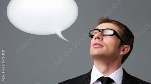 Man in suit looking up with speech bubble against gray background