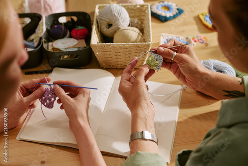 Foto Hands of Caucasian young adult women crocheting colorful yarn squares during creative workshop