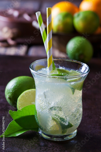 Fruit spritzer of limes in a glass with drinking straws
