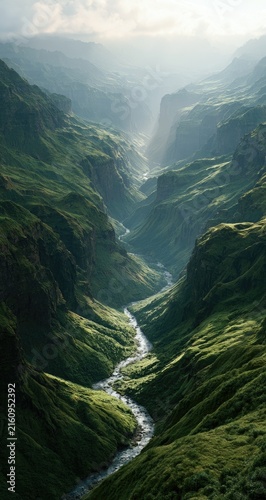 Sunlit river carves through lush, steep green mountain valley