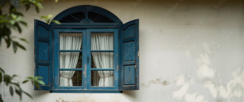 Obraz premium Blue Wooden Window with Open Shutters and White Curtains on a Wall