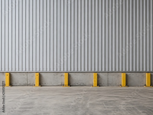 Industrial warehouse wall made of corrugated metal panels with yellow steel protective bumpers mounted on a concrete base at the floor level