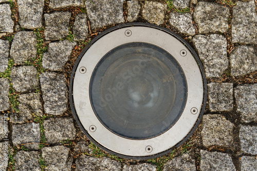 Foto Circular ground recessed light fixture embedded in textured grey granite cobbles