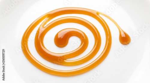 Golden Caramel Sauce Swirl Artistically Arranged on a Pristine White Background Plate