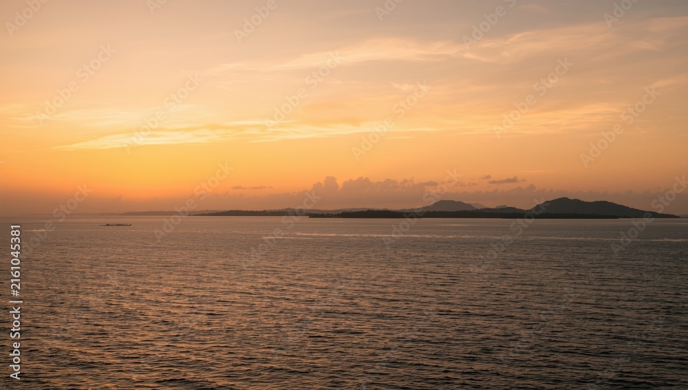 Obraz premium Serene Seascape at Sunset with Gentle Waves and Distant Islands