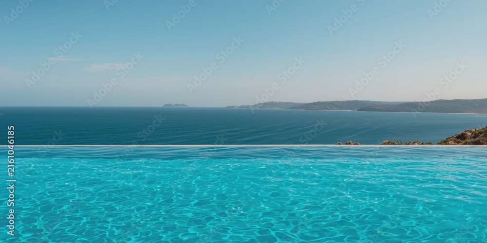Fototapeta premium Infinity Pool Overlooking a Calm Ocean Under Clear Blue Sky