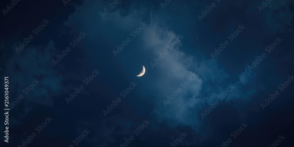 Fototapeta premium Crescent Moon Glowing Among Dark Clouds at Night
