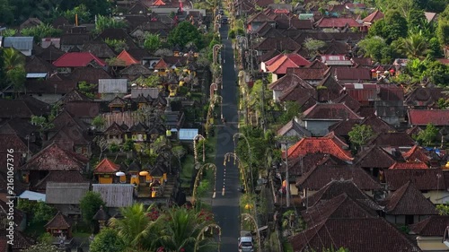 Aerial view of a traditional Balinese village decorated with ornate penjor bamboo poles along the main street in Kecamatan Tegallalang, Bali, Indonesia.