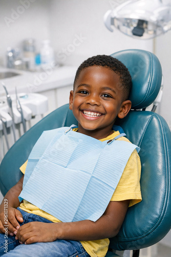 Smiling young boy sitting in the dentist chair for a dental check-up. He appears comfortable and happy, ready for his oral health routine.