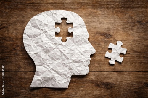 Crumpled Paper Cutout of Head with Missing Puzzle Piece on Wooden Background