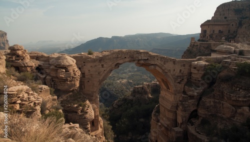Ancient Stone Arch Bridge Over a Valley in a Mountainous Landscape