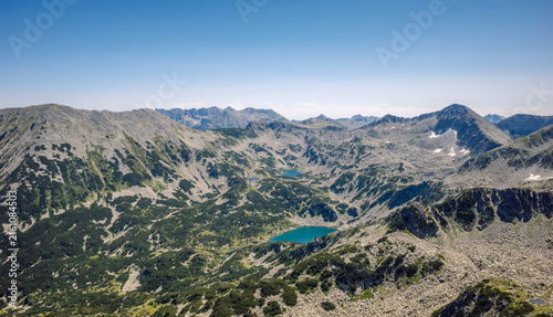 Rugged granite ridges, scree slopes, and deep turquoise glacial lakes of the Banderishki Lakes basin, as viewed from Muratov Peak in Pirin National Park, Bulgaria under a clear blue summer sky.