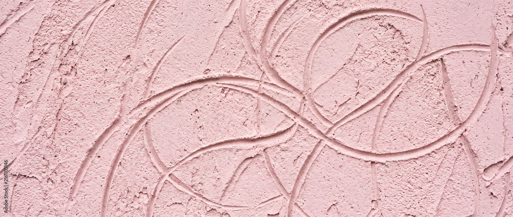 Fototapeta premium Macro close-up of a soft pastel pink plaster wall surface featuring intricate swirling hand-drawn texture patterns and artisanal finish