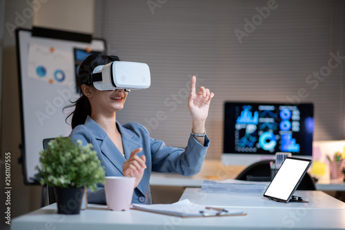 Asian Businesswoman Using VR Headset in Modern Office with Digital Data Displays