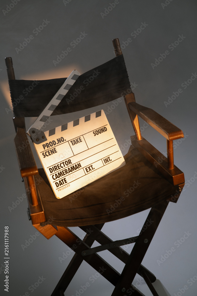 Fototapeta premium Movie director chair with clapboard slate under spotlight in film studio.