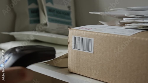 Worker scanning barcode on cardboard box package using handheld laser scanner, extreme close up. Footage is perfect for logistics, e-commerce shipping, and inventory management videos