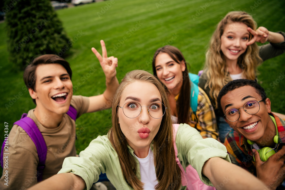 Obraz premium College friends taking a playful outdoor selfie on campus lawn — smiling students enjoying time together
