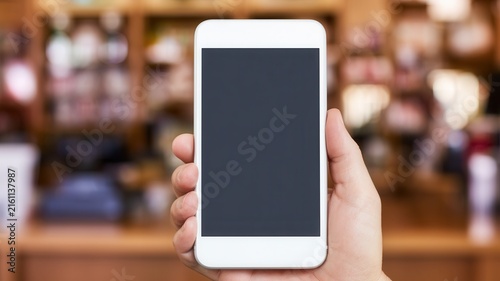 Hand holding a modern smartphone with blank screen in a business environment, representing mobile technology, digital communication, online services, applications, connectivity, and modern lifestyle.