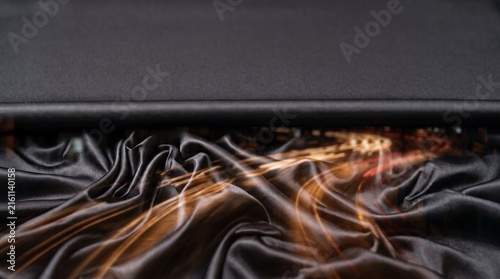 Abstract black silk fabric with cinematic glowing orange light trails.