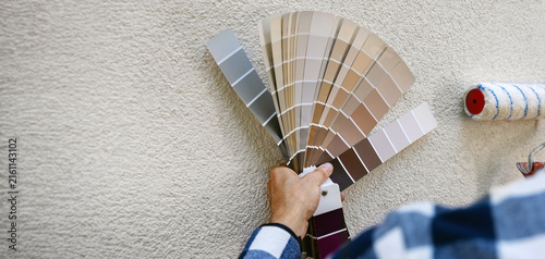 man choosing paint color from samples palette for house stucco plaster exterior. copy space