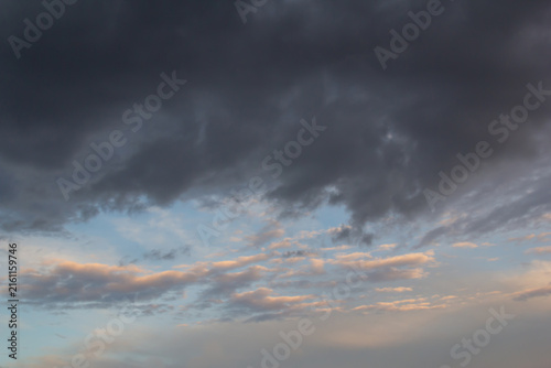 Dramatic storm clouds and soft sunset clouds over a moody evening sky at twil...