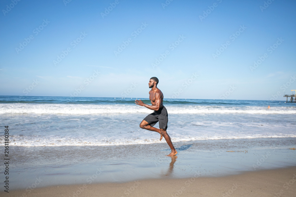 Fototapeta premium Man jogging along sandy beach.