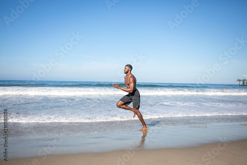 Man jogging along sandy beach.