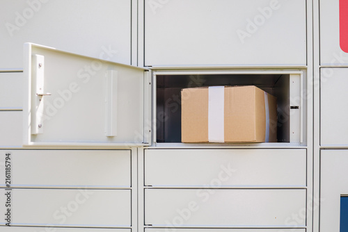 Fotografie Cardboard parcel inside an open compartment of an automated parcel locker ready for customer pickup