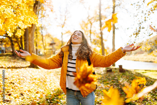 Photography Young woman stands in park strewn with yellow and orange leaves