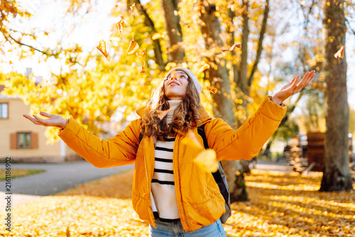 Фотография Young woman stands in park strewn with yellow and orange leaves