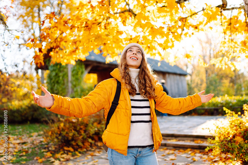 Photography Young woman stands in park strewn with yellow and orange leaves