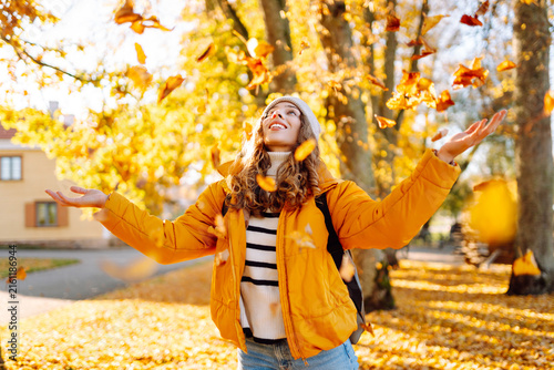 Obraz na plátně Young woman stands in park strewn with yellow and orange leaves