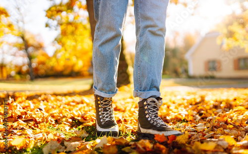 фотографія Close-up of hiker's feet walking through clearing strewn with yellow leaves at sunset