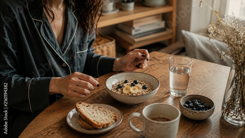Woman Eating Healthy Breakfast With Oatmeal and Fresh Fruit at Home