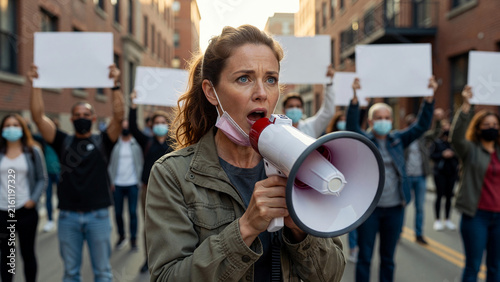 Determined female activist speaking into megaphone at urban protest, social awareness and community movement