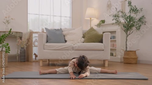 Child Practicing Seated Forward Bend on Yoga Mat in Bright Living Room with Plant and Daylight, Gentle Exercise for Flexibility, Wellness, Calm Movement, Mindful Stretching, Peaceful Home Scene