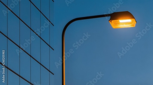 Urban lighting. LED street lamp illuminates a modern business district at dusk, providing outdoor lighting for roads, sidewalks and public spaces.