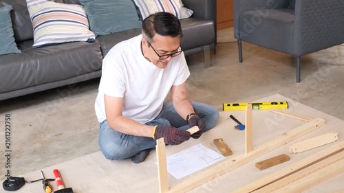 Furniture assembly senior man using wood tool in living room with instruction guide for home project near sofa chair