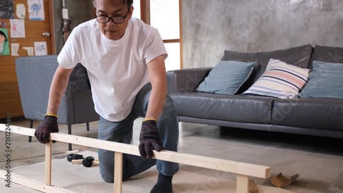 Furniture assembly wood frame in living room with adult man focused on home repair near sofa cushion and tool