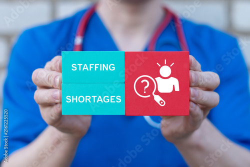 Concept of staffing shortages. Health care labor market crisis and recruitment challenges, magnifying glass over human resources.