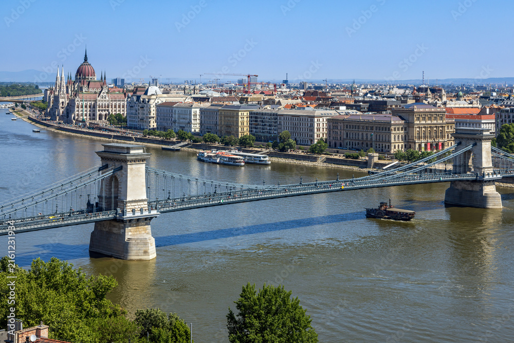 Obraz premium The historic Széchenyi Chain Bridge spanning the River Danube in Budapest, Hungary, with the grand Hungarian Parliament Building in the background.