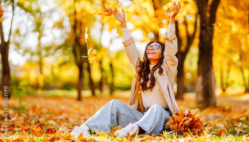 Konstfotografi Young woman sits in clearing in park strewn with autumn leaves at sunset