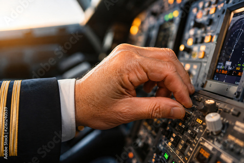 Airline pilot operating aircraft controls and instruments inside a modern cockpit
